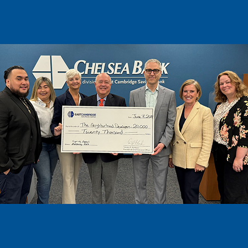 A group of representatives from the bank and The Neighborhood Developers hold a ceremonial check for $20,000 dollars.